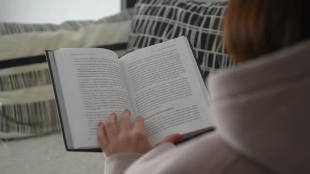 a fehér belső, a lány olvas egy könyvet, és lapozza a lapokat a hátsó nézet - Felvétel, videó