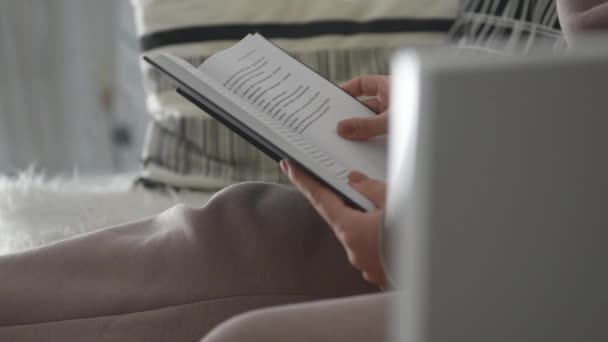 v bílém interiéru, dívka čte knihu a otáčí stránky v hladkém pohybu - Záběry, video