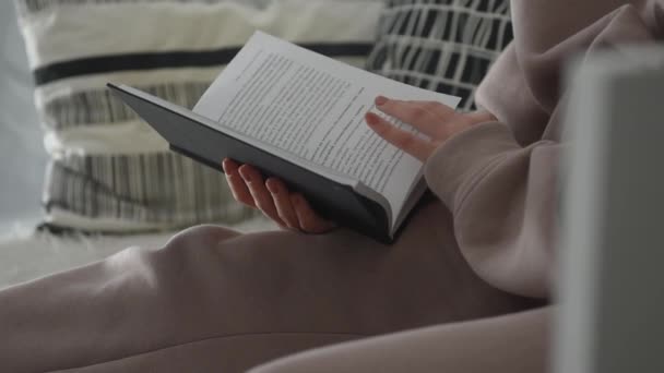 valkoinen sisustus, tyttö lukee kirjaa ja kääntää sivut vasemmalla puolella näkymä - Materiaali, video