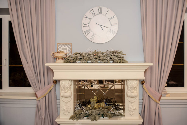 A decorated fireplace with fir branches, and a vintage clock above - Foto, Bild