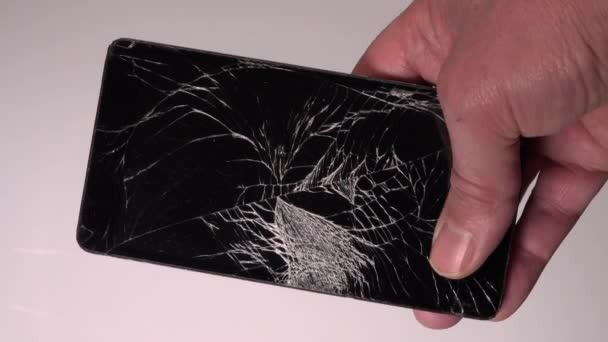 Smartphone con pantalla de vidrio roto en la mano. Vidrio roto en una pantalla. Choque de teléfono, fracturado, reparación. - Metraje, vídeo