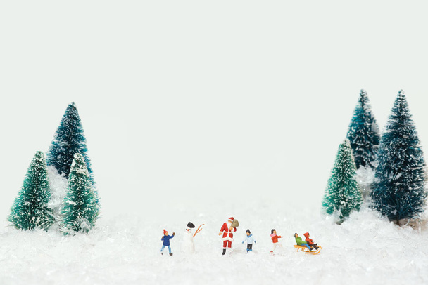 A Christmas scene of miniature figures of Santa Claus and kids playing in the snow - Φωτογραφία, εικόνα