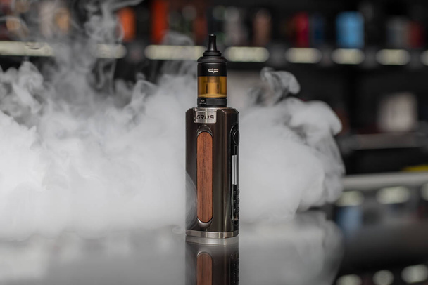 Electronic cigarette Lost Vape Grus Mod and Digiflavor Siren G MTL Tank with white smoke on the background.  - 写真・画像