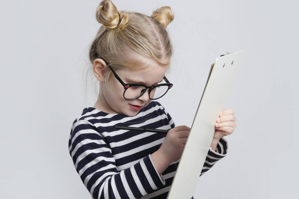 Portrait of adorable little girl with reading glasses, pen and paper. Business and education concept.  - Fotoğraf, Görsel