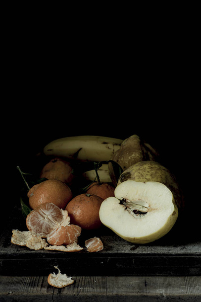 A closeup shot of fresh mandarins, apples and banana on a wooden table - Фото, зображення