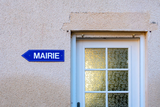 Blue directions sign with the word "town hall" written on it in French language, and attached to a wall next to an entrance door - 写真・画像