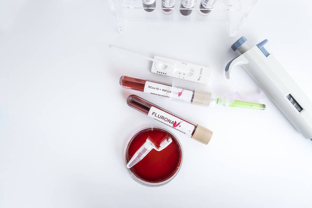 Blood samples of the new variant omicron plus flu FLURONA, covid19, coronavirus. Selective approach to the sample tube. - Foto, Imagem