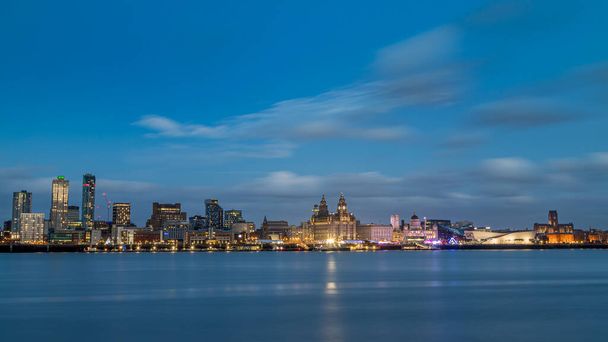 2022 yılının yılbaşı günü Liverpool siluetinin aynaya benzeyen Mersey Nehri 'ne bakan bir posta kutusu. Çerçevenin solundaki yeni binalar, görüntünün ortasında kaybolmaya başlar. Böylece Three Graces, the Royal Albert Rıhtımı ve  - Fotoğraf, Görsel