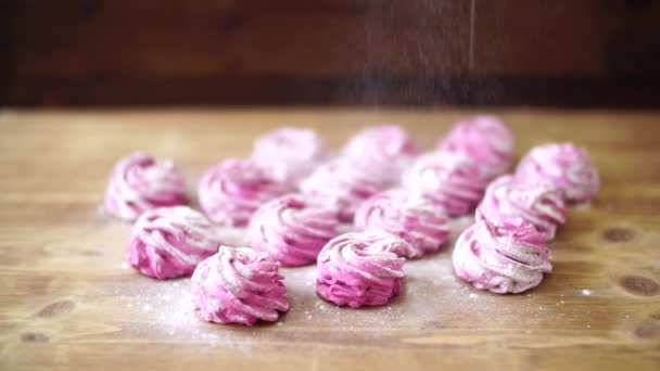 Sprinkling berry marshmallows met poedersuiker op een houten tafel - Video