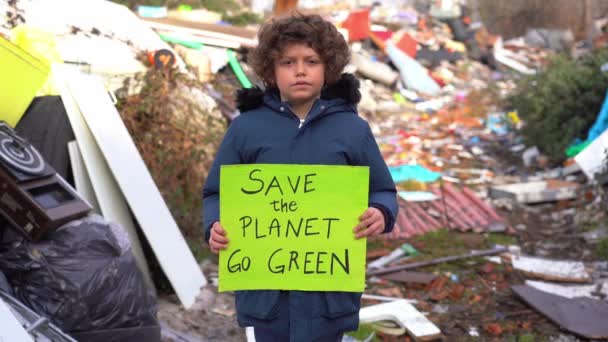 7-letni ekolog i ekolog trzymający znak ze słowami ratującymi planetę, protest przeciwko zmianom klimatu, globalnemu ociepleniu i zanieczyszczeniu atmosfery na wysypisku śmieci - Materiał filmowy, wideo