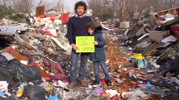 Ojciec 40 lat i syn 7 ekolog trzymając znak ze słowami uratować planetę przejść zielony, protest przeciwko zmianom klimatu, globalne ocieplenie i zanieczyszczenie atmosfery w śmietniku - Materiał filmowy, wideo