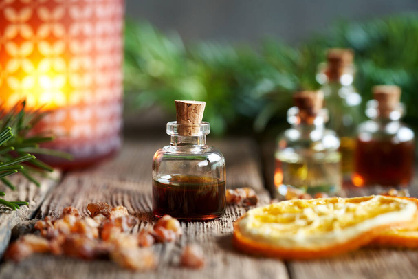 Christmas selection of aromatherapy essential oils with myrrh resin, orange and fir branches in the background - Fotó, kép