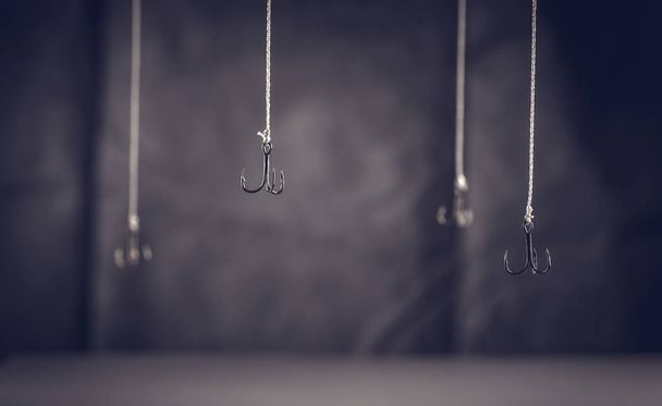 Fishing hooks hang on a dark background. Get hooked. Fall into the trap. Hook - Fotó, kép