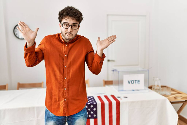 選挙室のそばに立つヒスパニック系の男は、腕や手との混乱した表現を提起した。疑わしい概念.  - 写真・画像