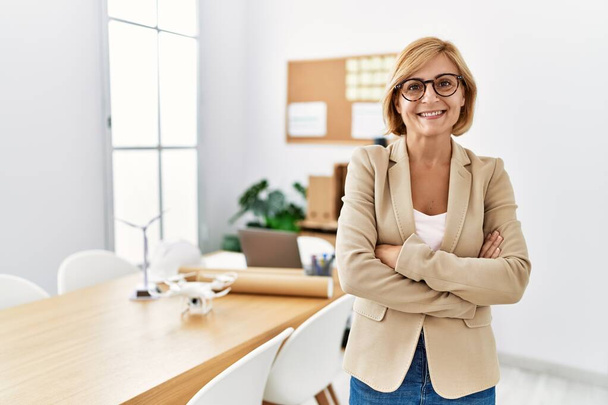 Middle age blonde woman smiling confident with arms crossed gesture at architecture studio - Foto, immagini