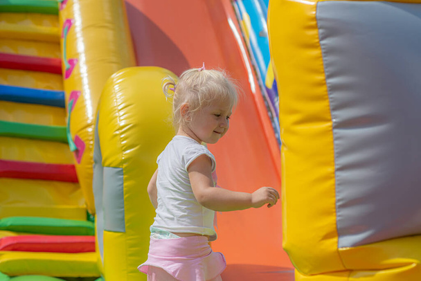 Joyful little girl jumping on an inflatable trampoline. - Photo, Image