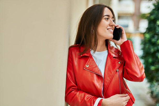 Junge hispanische Frau lächelt fröhlich auf dem Smartphone in der Stadt. - Foto, Bild