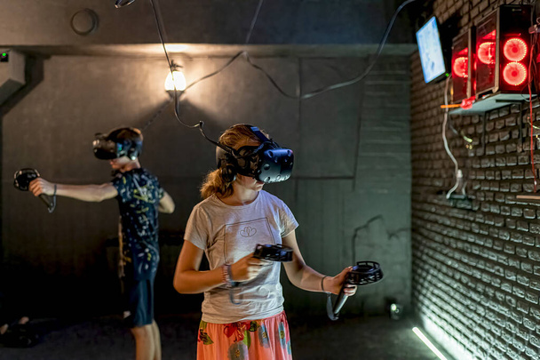Facet i dziewczyna w pokoju komputerowym grają w gry w kasku VR. - Zdjęcie, obraz