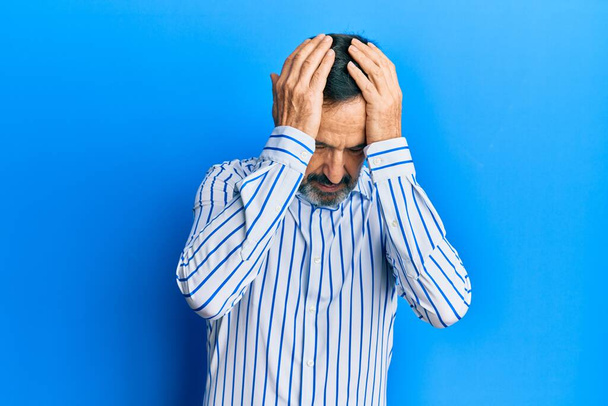 Homme hispanique du Moyen Âge portant des vêtements décontractés souffrant de maux de tête désespérés et stressés parce que la douleur et la migraine. mains sur la tête.  - Photo, image
