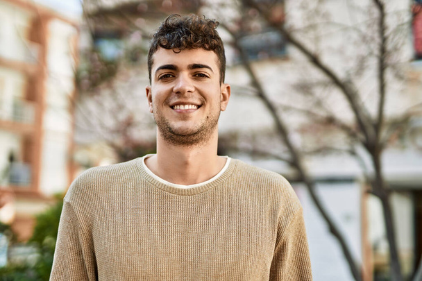 A fiatal spanyol férfi boldogan mosolyog a városban. - Fotó, kép