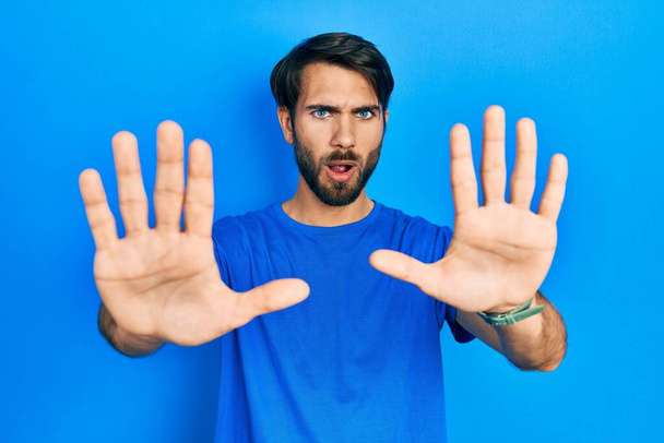 Young hispanic man wearing casual clothes doing stop gesture with hands palms, angry and frustration expression  - Fotoğraf, Görsel