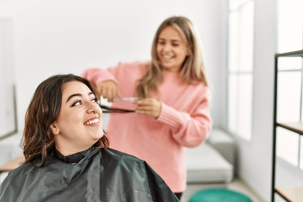 Молодая женщина стрижет волосы своей девушке дома. - Фото, изображение