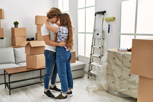 Joven pareja caucásica sonriendo confiados abrazándose en su nuevo hogar - Foto, Imagen