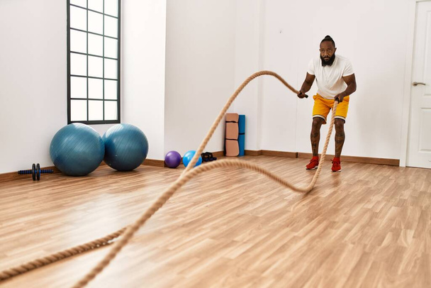 Młody Afrykanin amerykański człowiek trening z liny bojowej w centrum sportowym - Zdjęcie, obraz