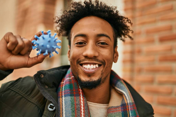 Young african american man smiling happy holding virus toy at the city - Photo, image