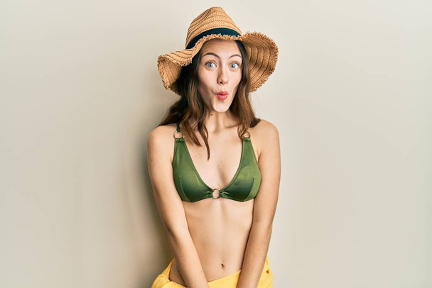 Young brunette woman wearing bikini afraid and shocked with surprise expression, fear and excited face.  - Photo, Image