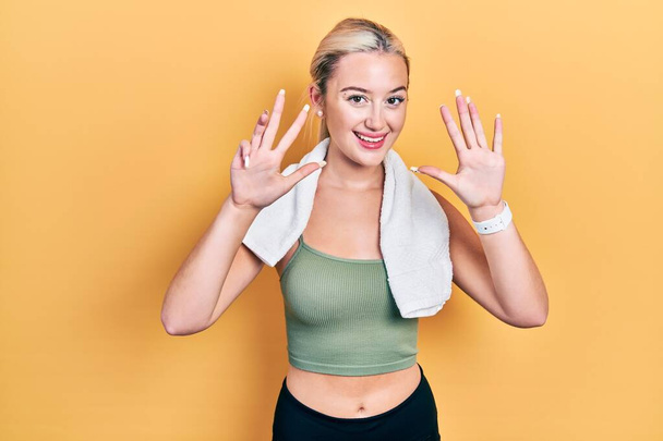 Young blonde girl wearing sportswear and towel showing and pointing up with fingers number nine while smiling confident and happy.  - Φωτογραφία, εικόνα