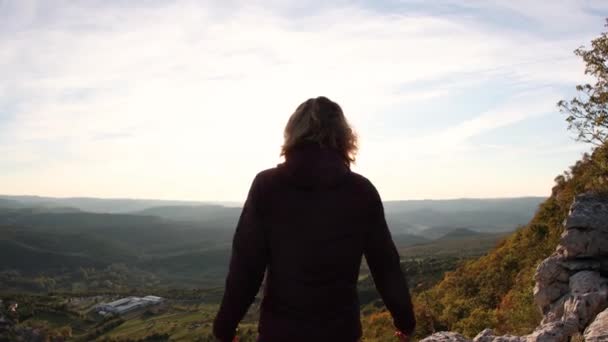 Jong meisje stak haar handen op naar de zon tegen de achtergrond van de bergen, slow motion - Video