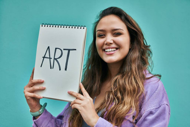 Молодая испаноязычная студентка улыбается счастливо держа блокнот в городе. - Фото, изображение