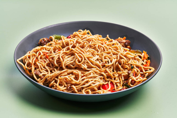  Πιάτο από νόστιμα noodles πάνω από πράσινο φόντο - Φωτογραφία, εικόνα