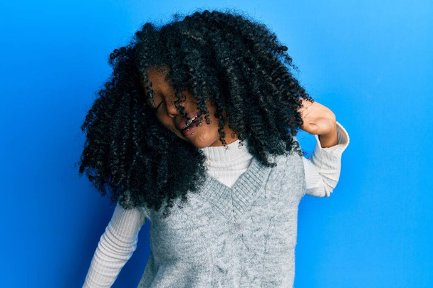 Αφροαμερικανή γυναίκα με αφρο μαλλιά φορώντας casual χειμερινό πουλόβερ που εκτείνεται πίσω, κουρασμένος και χαλαρός, υπνηλία και χασμουρητό για νωρίς το πρωί  - Φωτογραφία, εικόνα