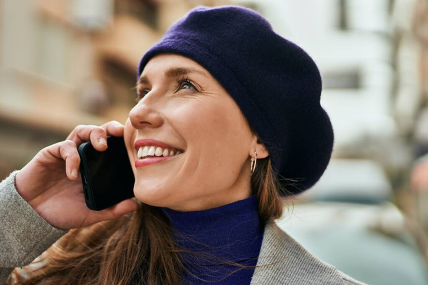 Mujer rubia joven sonriendo feliz hablando en el teléfono inteligente en la ciudad. - Foto, Imagen