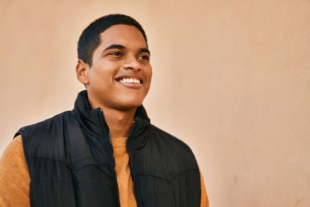 Fiatal latin férfi mosolyog boldog áll a városban - Fotó, kép