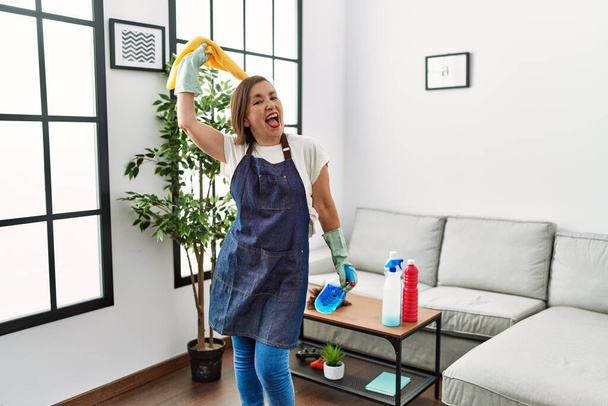 Middle age hispanic woman working as housekeeper dancing at home - Foto, Imagem