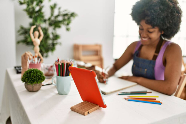 Young african american woman smiling confident looking touchpad drawing at art studio - Foto, imagen