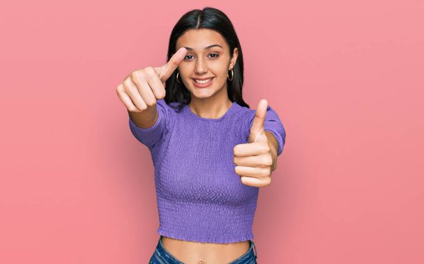 Young hispanic girl wearing casual clothes approving doing positive gesture with hand, thumbs up smiling and happy for success. winner gesture.  - Фото, зображення