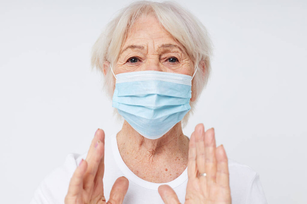 Photo of retired old lady in casual t-shirt and medical mask isolated background - 写真・画像