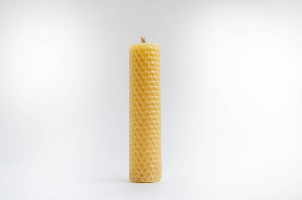 Yellow round wax candles with a honeycomb pattern on a white background - 写真・画像