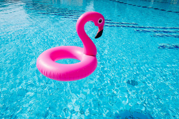 Zabawka flamingowa. Różowy dmuchany flaming w wodzie basenowej na letnie tło plaży. Luksusowy styl życia podróży - Zdjęcie, obraz