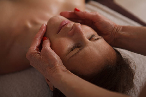 Gros plan d'une femme mature bénéficiant d'un massage facial par un cosmétique - Photo, image
