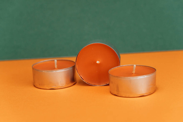 A closeup of decorative candles on orange and gre background - Fotoğraf, Görsel
