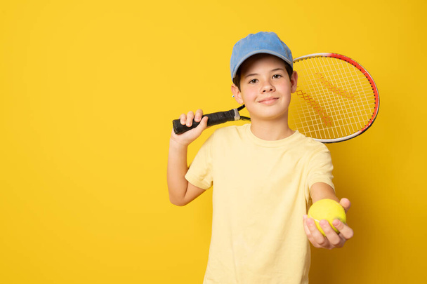 Smiling boy playing tennis holding racket isolated on yellow background - Foto, Bild