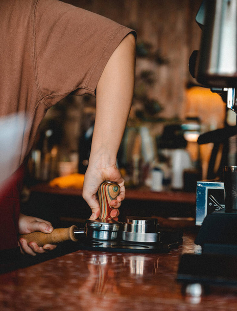 A barista pressing ground coffee with a metal tamper in the cafe - Foto, immagini