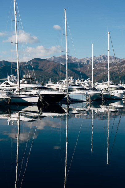 Sailing yachts are moored on the pier with the mountains in the background. Porto, Montenegro - Фото, изображение