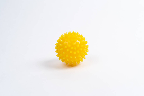 yellow ball of a massage needle on a white background, the concept of prevention of flat feet, hallux valgus, copy space - Photo, Image