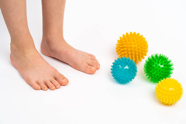 kolorowe kulki igłowe do masażu i fizjoterapii na białym tle z wizerunkiem stóp dzieci, koncepcja zapobiegania i leczenia haluksów valgus - Zdjęcie, obraz